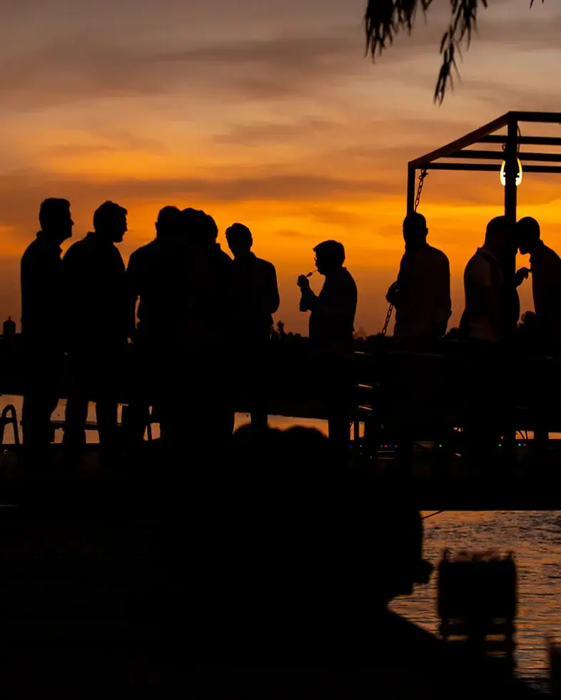 Silhuetas de pessoas confraternizando ao pôr do sol