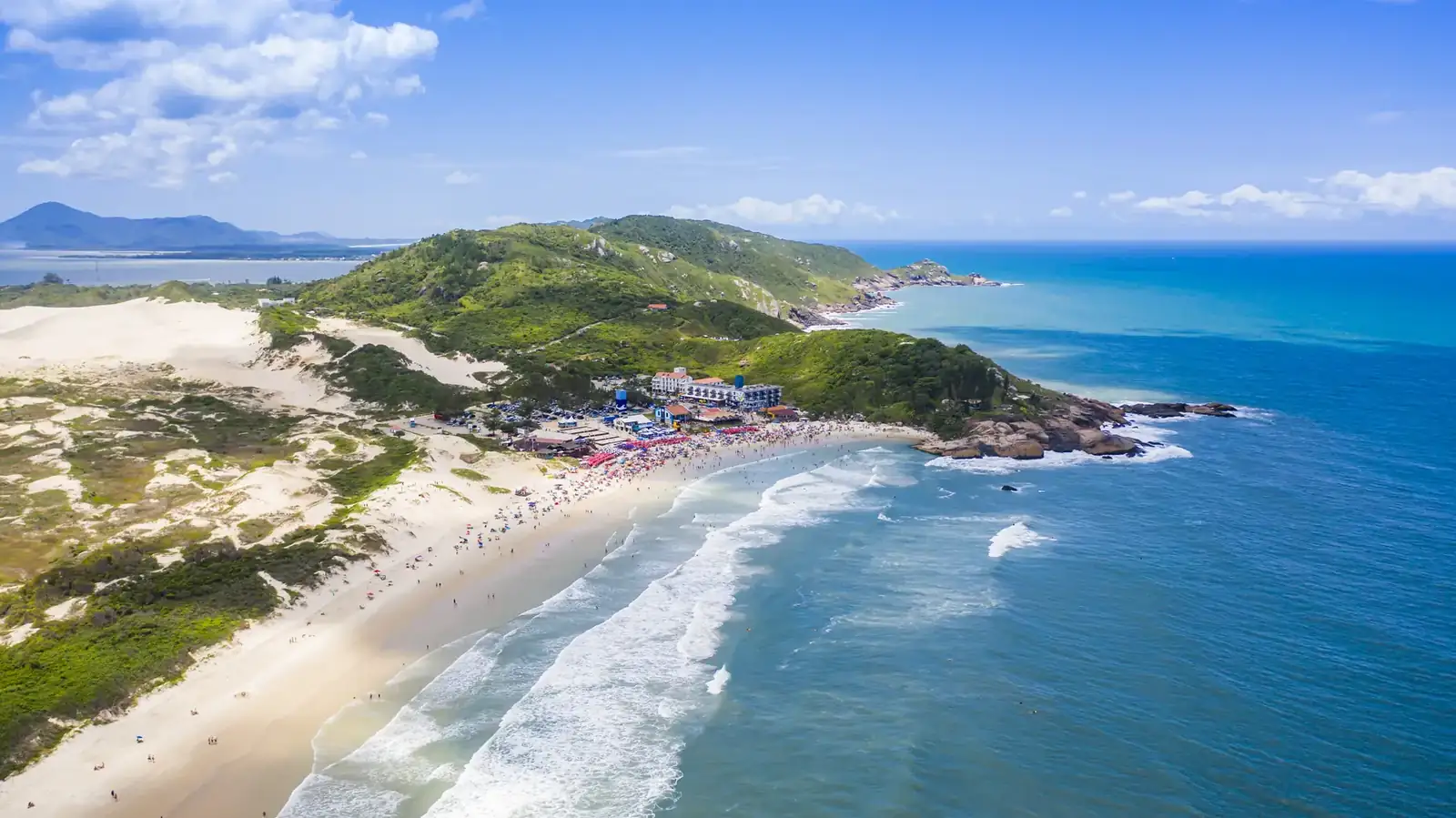 Dunas de areia branca com surfista ao fundo