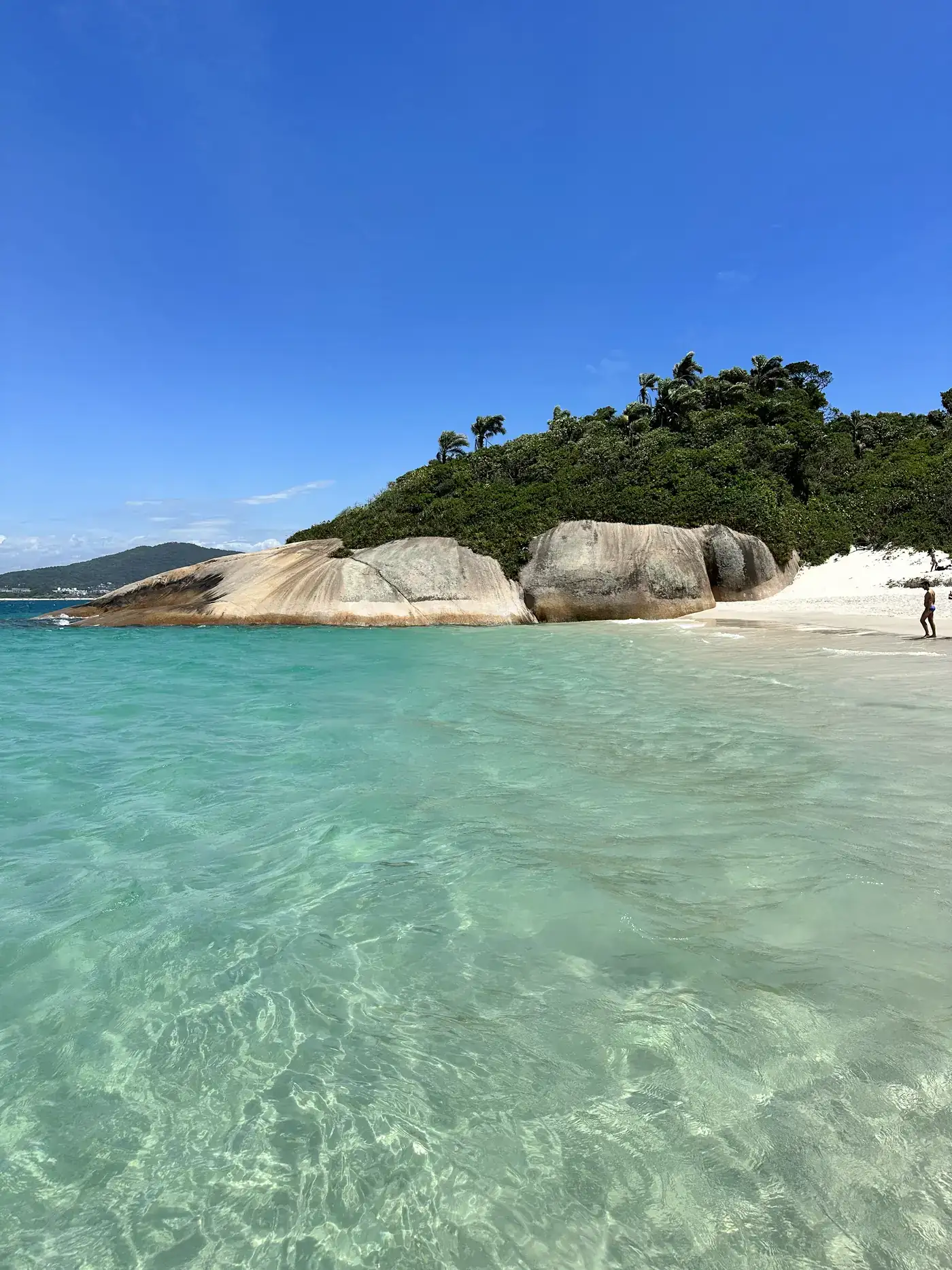 Água cristalina batendo em pedras na costa da ilha